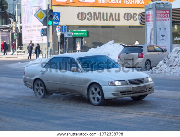 Novosibirsk, Russia - march 09 2021: private white\
metallic old japanese rwd rear wheel drive car Toyota Chaser X100,\
fullsize sport sedan from Japan from 90s 2000s driving on dirty\
winter snow street