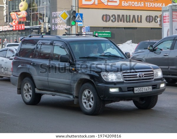 Novosibirsk, Russia - march 10 2021: private awd\
all-wheel drive black metallic color japanese old classic frame\
crossover 4x4 4wd 90s 2000s Toyota Land Cruiser 100, car SUV\
driving dirty broad\
street