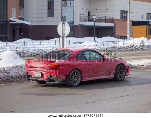 Novosibirsk, Russia - march 10 2021: private deep\
red metallic old japanese rwd rear wheel drive car Nissan Silvia\
S15, old classic sport coupe from Armenia from 90s 2000s driving\
winter snow street