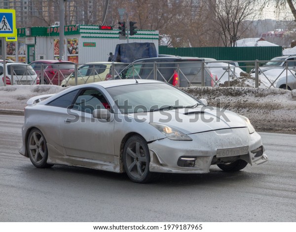 Novosibirsk, Russia - march 11 2021: private\
silver gray metallic old japanese fwd front wheel drive car Toyota\
Celica with low profile, old classic sport coupe 90s 2000s driving\
on dirty city\
street