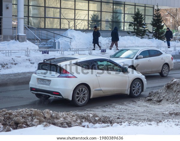 Novosibirsk, Russia - march 11 2021: private fwd front\
wheel drive white metallic japanese small hatch car Honda CR-Z\
Hybrid, rare hatchback export import driving on unclean snow dirty\
winter street 