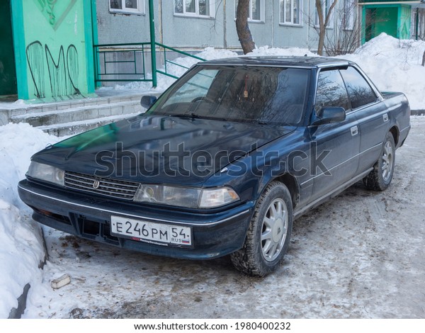 Novosibirsk, Russia - march 11 2021: private blue\
metallic old japanese rwd rear wheel drive car Toyota Mark II X80,\
midsize sport sedan made in Japan from 80s 90s parking on snow\
winter street yard