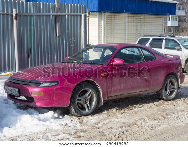 Novosibirsk, Russia - march 11 2021: private fwd\
front wheel drive crazy pink color metallic japanese sport coupe\
racing race car tuned modified Toyota Celica, export import parking\
snow winter street