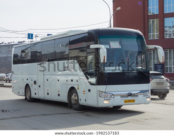 Novosibirsk, Russia - march 15 2021: white\
metallic color big long chinese new touristic chartered tour bus\
Yutong ZK6122, private transfer service vehicle made in China\
driving on city urban\
street