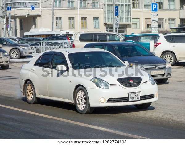 Novosibirsk, Russia - march 15 2021: private white\
metallic old japanese rear wheel drive car rare Toyota Verossa,\
midsize sport sedan made in Japan from 2000s driving spring dirty\
city urban street