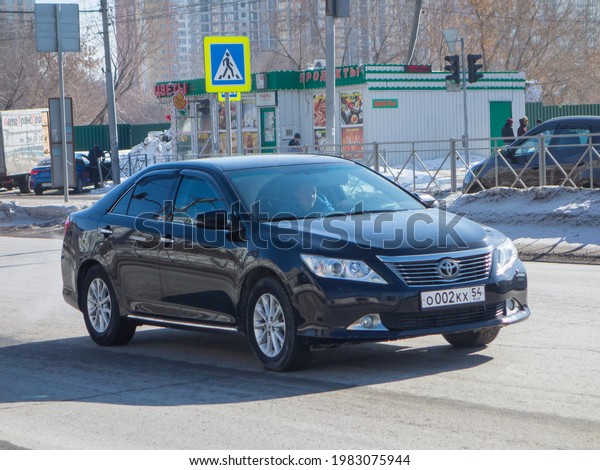 Novosibirsk, Russia - march 16 2021: private black\
metallic japanese fwd front wheel drive car  Toyota Camry XV50,\
midsize premium popular sedan made in Japan export import driving\
dirty urban street