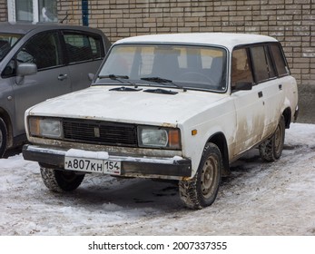 Novosibirsk, Russia - March 19 2021: White Metallic Color Russian Rwd Drive Old Classic Vintage Station Wagon VAZ Lada 2104 Zhiguli, Made In Soviet Union Parking On Snow Winter Urban Unpaved Street