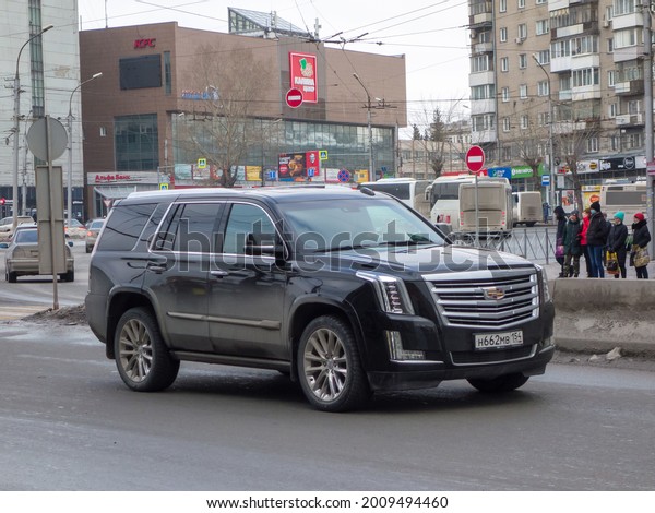 Novosibirsk, Russia - March 22 2021: private awd\
all-wheel drive black metallic color north american new car SUV\
Cadillac Escalade, USDM US-spec crossover exported made in USA\
driving on urban street\
