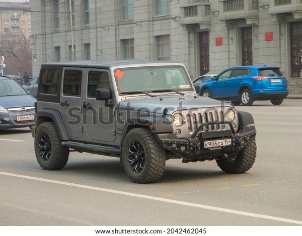 Novosibirsk, Russia - march 24 2021: private all-wheel\
drive gray metallic color north american car SUV Jeep Wrangler\
Unlimited Sport JK, USDM US-spec crossover made in USA driving on\
broad street 