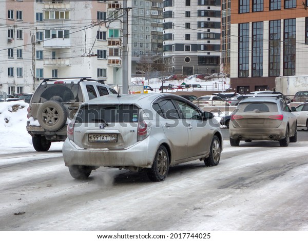 Novosibirsk, Russia - march 29 2021: private fwd\
drive silver gray metallic japanese small cheap hatch car Toyota\
Prius c Aqua popular hatchback export import on snow lift dirty\
slippery winter\
street