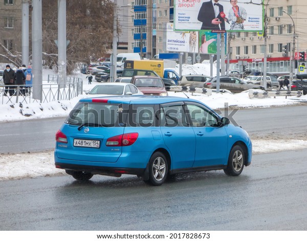 Novosibirsk, Russia - march 29 2021: private sky\
blue metallic color station wagon japanese old car Nissan Wingroad,\
2000s car export import made in Japan driving in spring urban sleet\
slush street