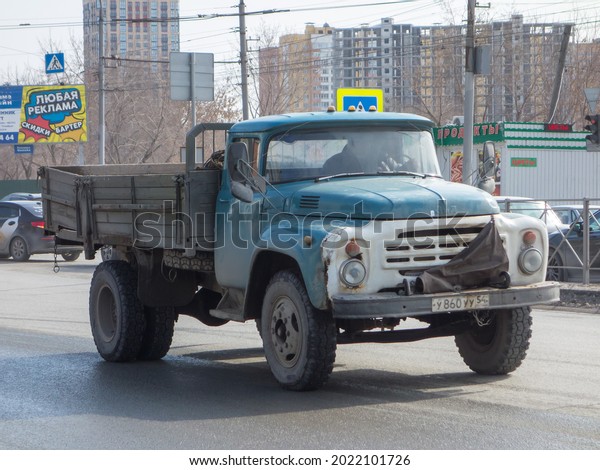 Novosibirsk, Russia - march 31 2020: White blue\
metallic color rusty small heavy flatbed dump truck chassis car ZiL\
130 (4314), old classic vintage made in Soviet Union USSR on urban\
broad street