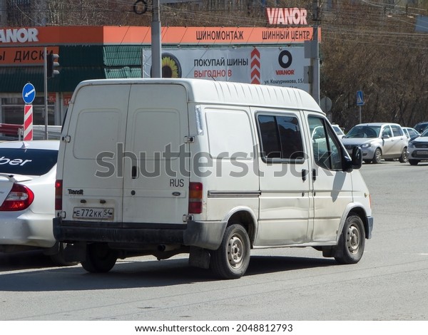 Novosibirsk, Russia - may 04 2021: private white\
metallic color old classic cargo passenger all-metall midsize van\
90s Ford Transit short base SWB, european eu popular car stop drive\
on city street