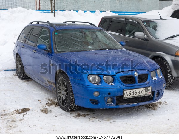 Novosibirsk, Russia - May 05 2021: private\
all-wheel drive dark deep blue metallic british sport station wagon\
MG ZT-T based on Rover 75, old car from 90s 2000s from UK parking\
on snow winter\
street