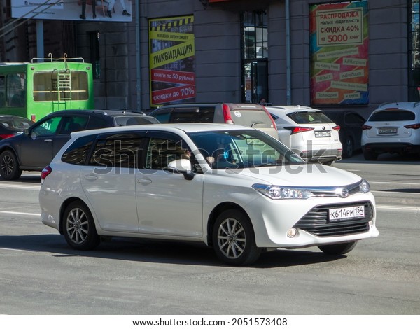 Novosibirsk, Russia, may 06 2021: private fwd\
white metallic color japanese midsize economy car Toyota Corolla\
Fielder E160 facelift, estate station wagon made in Japan drive on\
city urban street