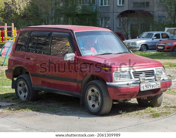 Novosibirsk, Russia, may 11 2021: private\
all-wheel drive red vinous metallic color japanese frame SUV Suzuki\
Escudo Nomade 80s 90s, popular old retro car crossover parking on\
city urban sunny\
street
