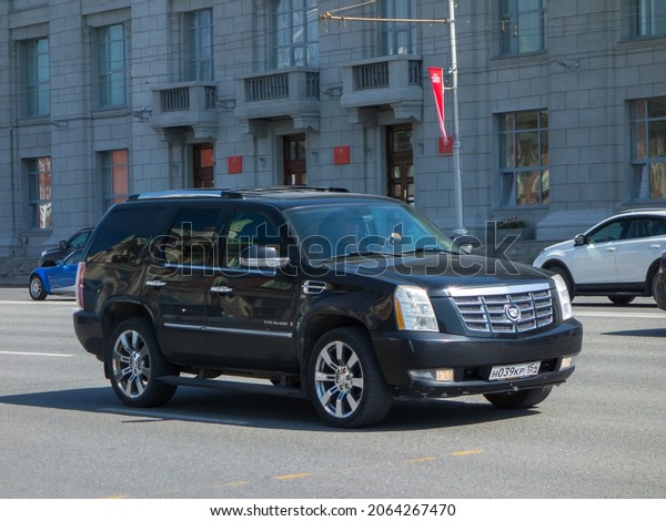 Novosibirsk, Russia - may 12 2021: private awd all-wheel\
drive black metallic color north american new car SUV Cadillac\
Escalade, USDM US-spec crossover exported made in USA driving on\
urban street 