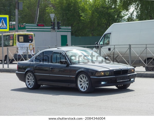 Novosibirsk, Russia, may 17 2021: private black\
metallic color premium sedan old 90s BMW 7-Series 750i E38 xDrive,\
luxury heavy business class car long base made in Germany drive on\
sunny urban street