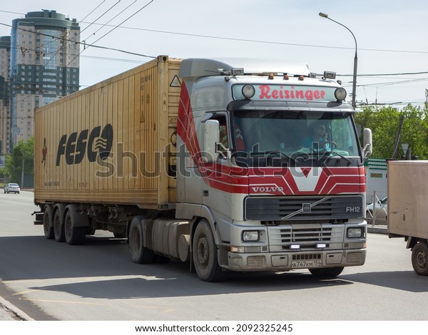 Novosibirsk, Russia, may 19 2021: swedish\
multi-wheeled silver gray red vinyl metallic color old big Fesco\
company owned container truck 90s Volvo FH 12, popular european\
cabover drive on urban\
street