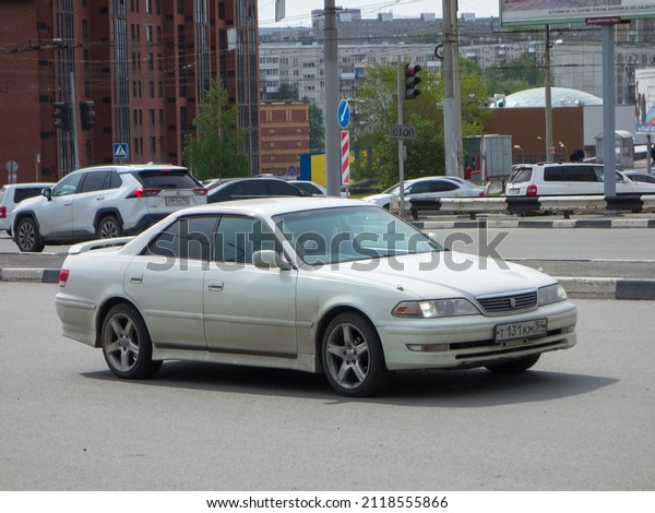 Novosibirsk, Russia, may 21 2021: private white metallic\
old japanese rear wheel drive sport car Toyota Mark II X100,\
midsize sport sedan made in Japan from 90s 2000s drive on broad\
city urban street 