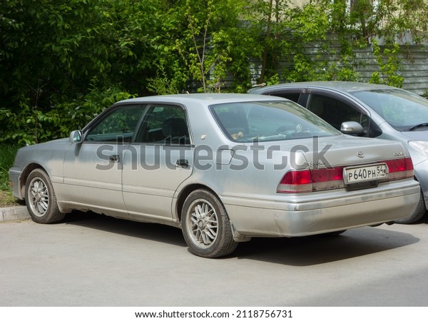 Novosibirsk, Russia, may 21 2021: private silver\
gray metallic dirty old frame long japanese rear-wheel drive car\
Toyota Crown S150, popular vintage 90s sedan made in Japan parking\
urban city street