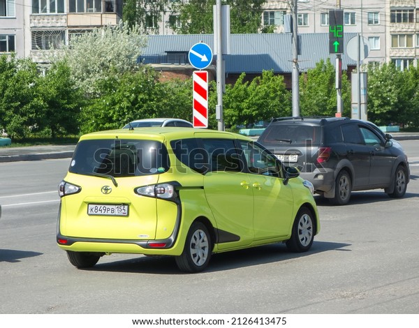 Novosibirsk, Russia, may 26 2021: private new\
crazy lime color metallic color passenger japanese minivan car\
Toyota Sienta II 2 XP170 mini van export import made in Japan drive\
on urban broad\
street