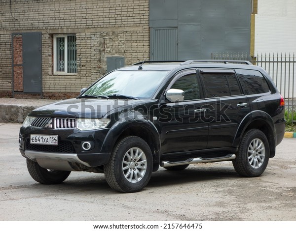 Novosibirsk, Russia - may 28 2021: private awd\
all-wheel drive black graphite metallic color japanese frame\
crossover 4x4 4wd used Mitsubishi Pajero Sport car SUV parking on\
urban street in\
backyard