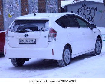 Novosibirsk, Russia - November 29 2019: Private White Metallic Color Metallic Japanese Family Car Toyota Prius α Alpha, Hybrid Minivan Station Wagon Made In Japan On Urban Winter Snow Street In Yard