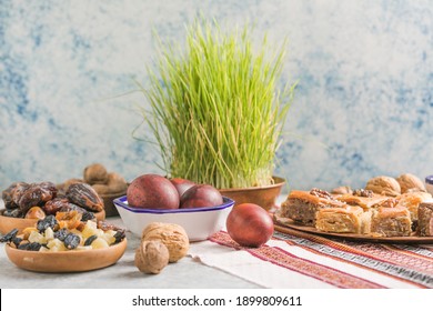 Novruz traditional tray with green wheat grass semeni or sabzi, sweets and dry fruits pakhlava on white background. Spring equinox, Azerbaijan copy space