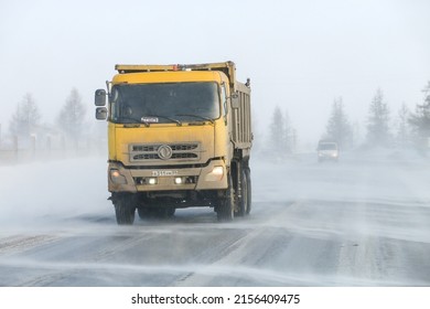 Novyy Urengoy, Russia - April 20, 2022: Yellow Dump Truck DongFeng DFL3251 In A City Street During A Strong Wind And Snowfall.