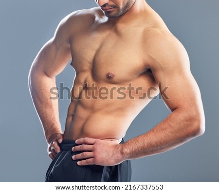 Now thats definitely not an average body. Studio shot of a muscular young man posing against a grey background.