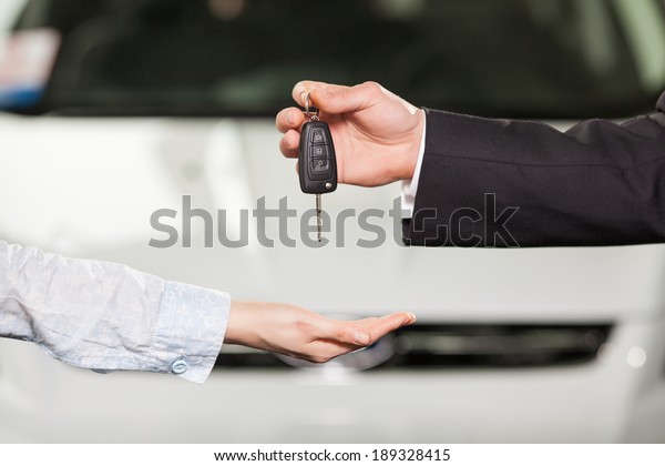 Now this car is yours. Car salesman giving the key\
to the new car owner