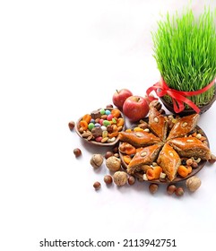 Nowruz festive table. green wheat grass with red ribbon, arabic dessert baklava, sweets, nuts, dry fruits. Traditional celebration of spring equinox in March, Nowruz Holiday