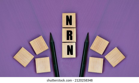 NRN (Not Right Now) - acronym on wooden cubes with pencils on a purple background. Internet slang concept
