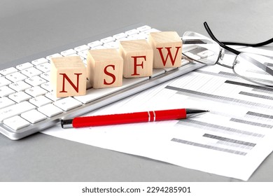 NSFW written on wooden cube on the keyboard with chart on grey background