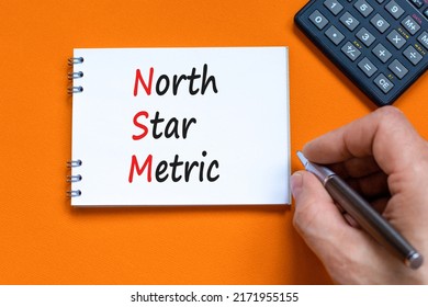 NSM North Star Metric Symbol. Concept Words NSM North Star Metric On White Note On A Beautiful Orange Background. Businessman Hand. Business And NSM North Star Metric Concept. Copy Space.