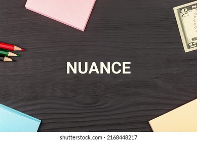 NUANCE - text, money dollars, stickers and colored pencils on a black wooden table. Business concept: buying, selling, commerce (copy space).