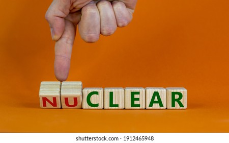 Nuclear or clear symbol. Businessman turns a cube and changes the word 'nuclear' to 'clear'. Beautiful orange background. Nuclear or clear and business concept. Copy space. - Shutterstock ID 1912465948