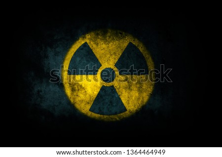 Nuclear energy radioactive (ionizing atomic radiation) round yellow symbol shape painted on massive concrete cement wall texture dark background. Nuclear radiation or radioactive alert warning danger.
