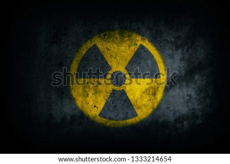 Nuclear energy radioactive (ionizing radiation) round yellow symbol shape painted on massive concrete cement wall grungy texture dark background. Nuclear radiation or radioactive alert concept.