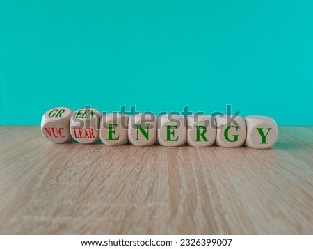 Nuclear or green energy symbol. Turned wooden cubes and changes concept words nuclear energy to green energy. Beautiful blue background copy space. Wooden table. Business nuclear green energy concept.