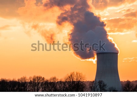 Nuclear power plant with bright orange sunset and forest