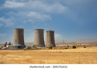 Nuclear power plant cooling towers, big chimneys beside Wheat field with partly cloudy sky in Kurdistan province, iran