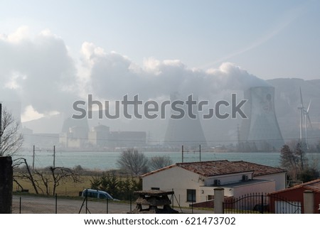 nuclear power plant in Cruas, France produces steam from reactors; in front river Rhone, railway and house