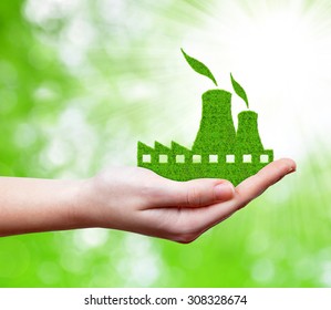 Nuclear power plant icon in hand on green natural background.
