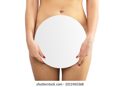 Nude beautiful woman holding a round sign in her hands and covering them with genitals on a white background isolate. Lower body
