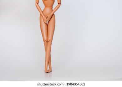 Nude doll covering pelvic area on white background. Female figure having UTI problems.