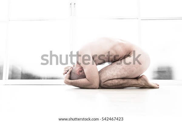 Nude man with fetal\
position in white room