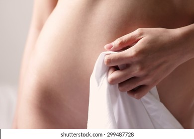 Nude woman holding cloth over her vagina