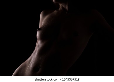 Nude young woman with piercings in her nipples. Beautiful athletic body. Silhouette of a woman.